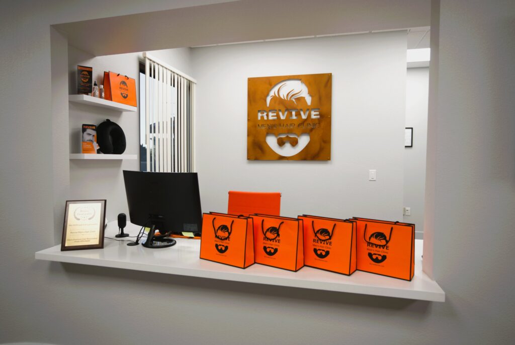 Front desk with the Revive metal logo at Revive Mens Hair Clinic
